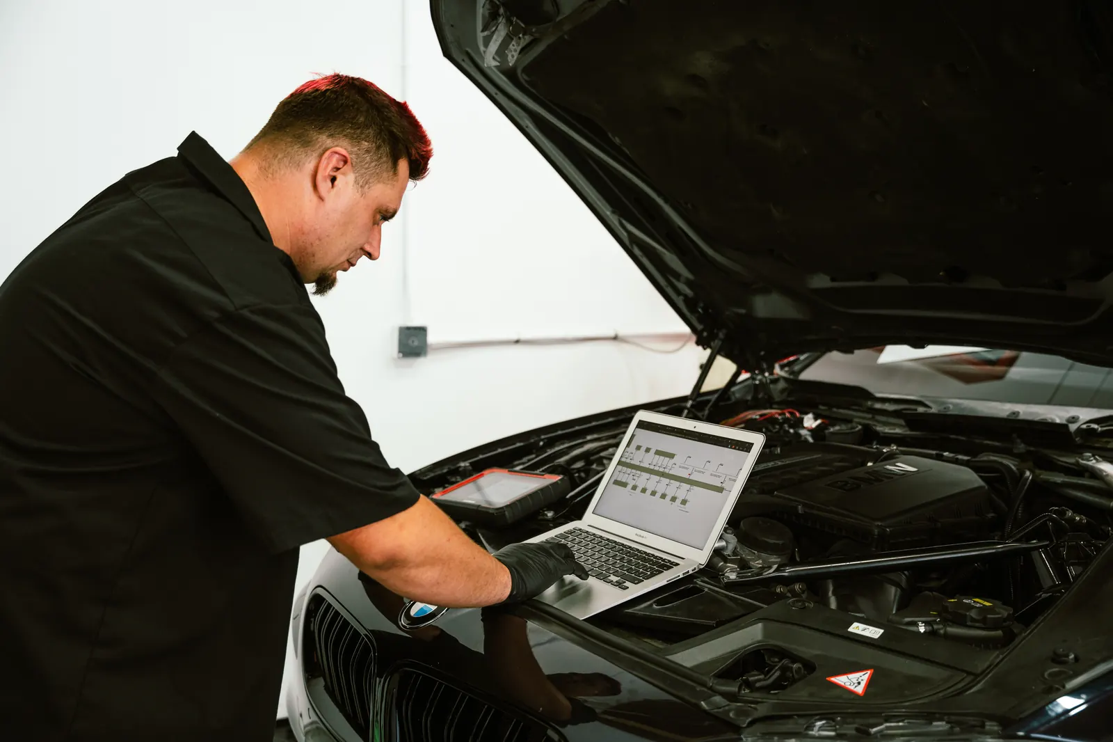 Mechanic running a laptop engine diagnostic scan in Escondido, CA