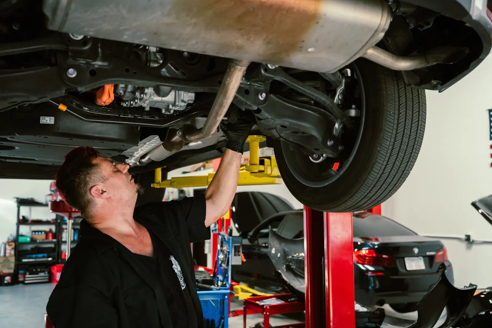 Mechanic inspecting exhaust system underneath a vehicle in Escondido, CA